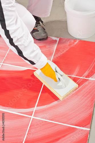 Photo: worker clean with sponge trowel tile joints grout worker clean with sponge trowel tile joints grout