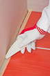 worker with tool smooth silicone sealant on corner with tiles