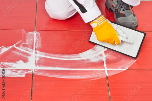 Photo: worker with rubber trowel applying grout tile worker with rubber trowel applying grout tile