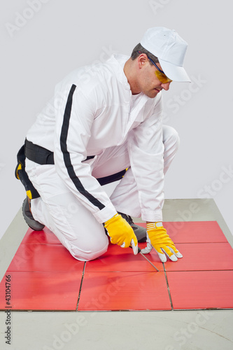 Photo: Worker with Sharp tool clean spaces between tiles remove tile ad Worker with Sharp tool clean spaces between tiles remove tile ad