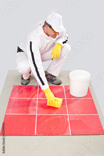 Photo: worker with yellow gloves and yellow sponge clean tiles worker with yellow gloves and yellow sponge clean tiles