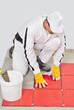 Photo: worker with bucket adhesive apply red tiles worker with bucket adhesive apply red tiles