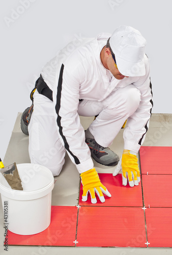 Photo: worker with bucket adhesive apply red tiles worker with bucket adhesive apply red tiles