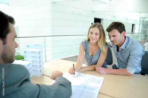 Photo: Couple in real-estate agency signing contract Couple in real-estate agency signing contract