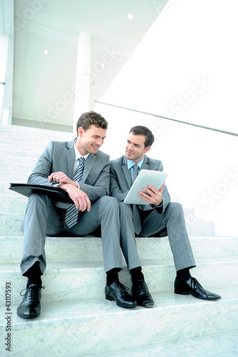 Photo: Business meeting in stairs with electronic tablet Business meeting in stairs with electronic tablet