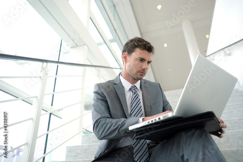 Foto: Serious businessman sitting in stairs with laptop Serious businessman sitting in stairs with laptop