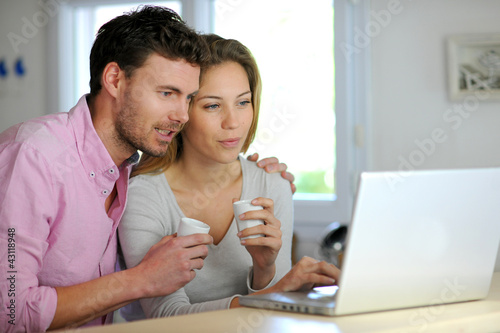 Foto : Happy couple websurfing on laptop computer at home Happy couple websurfing on laptop computer at home