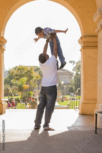 Photo: African American Father Lifting Mixed Race Son in the Park African American Father Lifting Mixed Race Son in the Park
