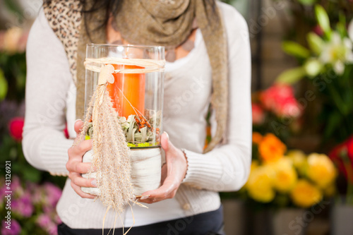 Photo: Floristin in Blumenladen mit Gesteck und Kerze Floristin in Blumenladen mit Gesteck und Kerze