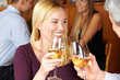 Lachende Frau prostet mit Wein zu