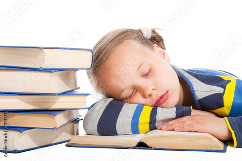 Photo: schoolgirl sleeping over the book on isolated white schoolgirl sleeping over the book on isolated white