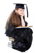 girl in black academic cap and gown reading big blue book