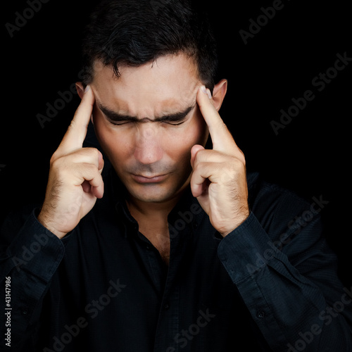 Photo: Man suffering from a strong headache isolated on black Man suffering from a strong headache isolated on black