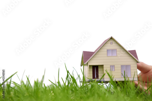 Photo: Hand holding the model of a house over green grass Hand holding the model of a house over green grass