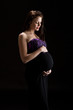 Beautiful brunette model looking lovingly at baby belly