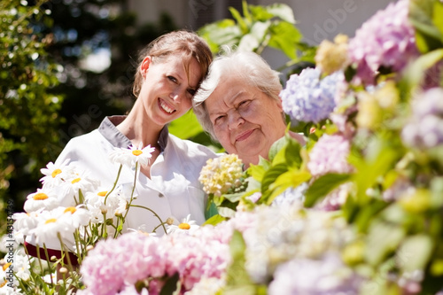 Foto: Altenpflegerin mit Seniorin im Garten Altenpflegerin mit Seniorin im Garten