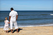 Father and daughter watching the horizon at the beach