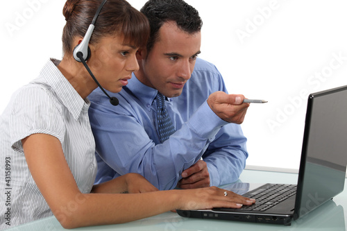 Photo: two office colleagues looking at a laptop two office colleagues looking at a laptop