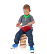 Foto: Kleiner Junge sitzt auf Bücherstapel und liest ein Buch Kleiner Junge sitzt auf Bücherstapel und liest ein Buch