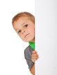 Kleiner Junge schaut hinter weißer Wand hervor