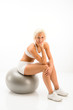Woman sitting on pilates ball white fitness
