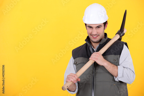 Photo: Playful young man holding a pickaxe Playful young man holding a pickaxe