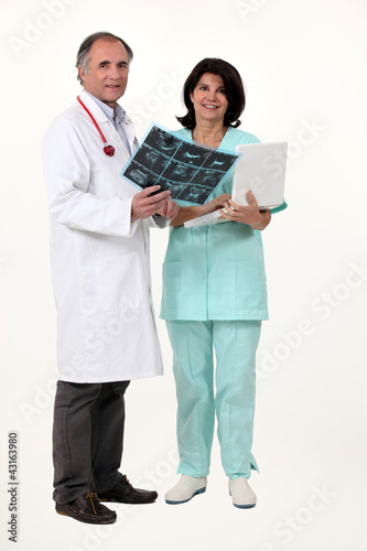 Photo: doctor and nurse examining a x-ray image doctor and nurse examining a x-ray image