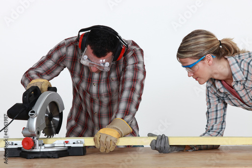 Foto: Couple sawing timber Couple sawing timber