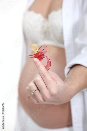 Photo: pregnant woman holding a pacifier pregnant woman holding a pacifier