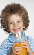 Foto: Niño sujetando un vaso de jugo de naranja,bebiendo jugo. Niño sujetando un vaso de jugo de naranja,bebiendo jugo.