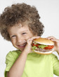 Foto: Niño comiendo hamburguesa,sujetando una hamburguesa. Niño comiendo hamburguesa,sujetando una hamburguesa.