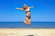 Foto: happy girl wearing bikini jumping on beach happy girl wearing bikini jumping on beach