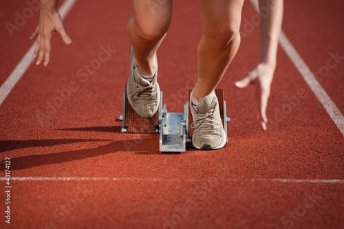 Photo: female sprinter leaving the starting blocks on a track female sprinter leaving the starting blocks on a track