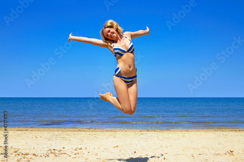 Foto: happy girl wearing bikini jumping on beach happy girl wearing bikini jumping on beach