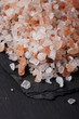 Coarse pink himalayan, sea salt on black slate stone background,