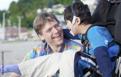 Photo: Father enjoying beach with disabled son Father enjoying beach with disabled son