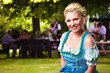 junge blonde Frau im Dirndl im Biergarten