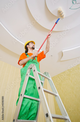 Photo: Painter worker during painting job Painter worker during painting job