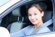 Girl in a car smiling to you.