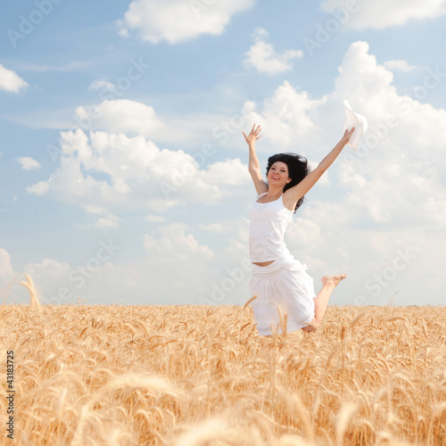 Foto: Happy woman jumping in golden wheat Happy woman jumping in golden wheat