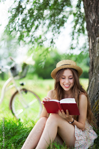 Photo: Young woman reading book outdoors Young woman reading book outdoors