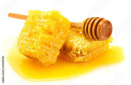 Photo: golden honeycombs and wooden drizzler with honey isolated golden honeycombs and wooden drizzler with honey isolated