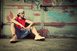 Photo: Young man sitting. Grunge graffiti wall Young man sitting. Grunge graffiti wall