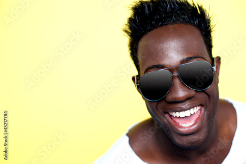 Photo: Closeup of joyful young african guy in sunglasses Closeup of joyful young african guy in sunglasses