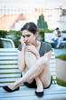 Depressed young woman sitting in a park full of happy couples