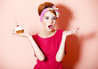 Style redhead girl with cake at pink background.