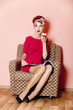 Style girl in red dress sitting in armchair with cake and magazi