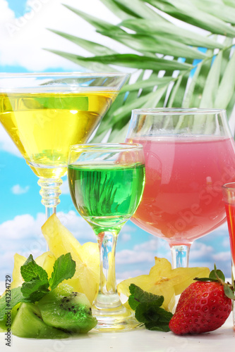 Foto: Glasses of cocktails on table on blue sky background Glasses of cocktails on table on blue sky background