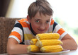 Foto: Portrait of a boy at the table with a plate of corn Portrait of a boy at the table with a plate of corn