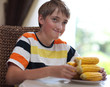 Foto: Portrait of a boy at the table with a plate of corn Portrait of a boy at the table with a plate of corn